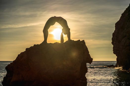 Girl gymnast is training on the beach by the sea sunset. Does twine. Photo series