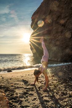Girl gymnast is training on the beach by the sea sunset. Does twine. Photo series