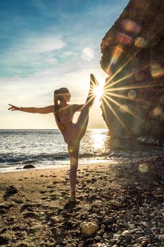 Girl gymnast is training on the beach by the sea sunset. Does twine. Photo series