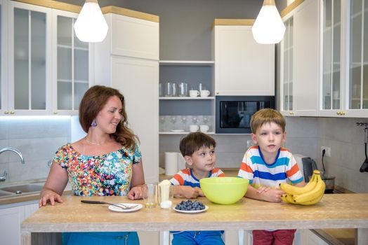 Young mother and her two kids at kitchen baking cookies.