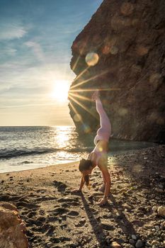 Girl gymnast is training on the beach by the sea sunset. Does twine. Photo series