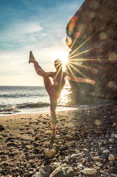 Girl gymnast is training on the beach by the sea sunset. Does twine. Photo series