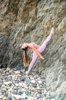 Girl gymnast is training on the beach by the sea. Does twine. Photo series.