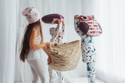 Children in soft warm pajamas playing in bed