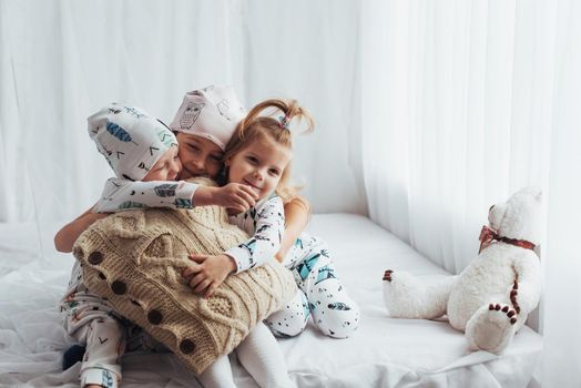 Children in soft warm pajamas playing in bed