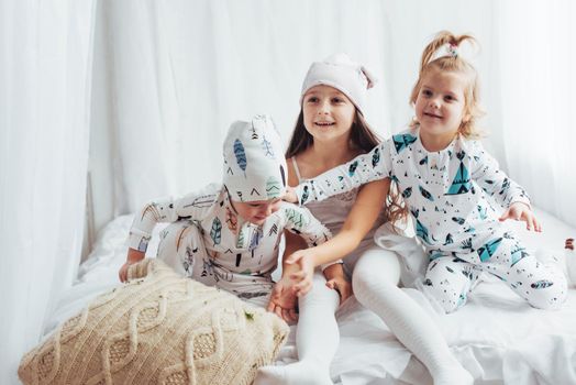 Children in soft warm pajamas playing in bed