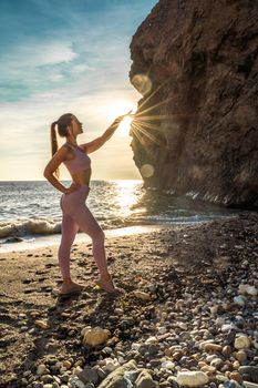 Girl gymnast is training on the beach by the sea sunset. Does twine. Photo series