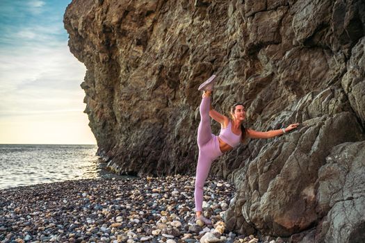 Girl gymnast is training on the beach by the sea. Does twine. Photo series.