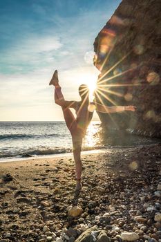 Girl gymnast is training on the beach by the sea sunset. Does twine. Photo series