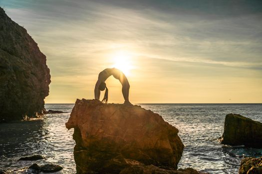 Girl gymnast is training on the beach by the sea sunset. Does twine. Photo series