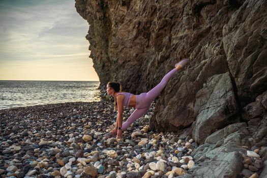 Girl gymnast is training on the beach by the sea. Does twine. Photo series.