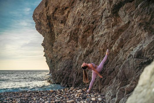 Girl gymnast is training on the beach by the sea. Does twine. Photo series.