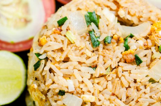 The fried rice and vegetable in black dish on tablecloth. Thai food style.