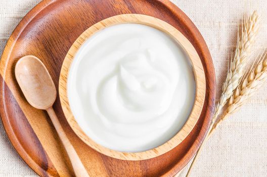 The Greek yogurt in a wooden bowl and dry barley on table.