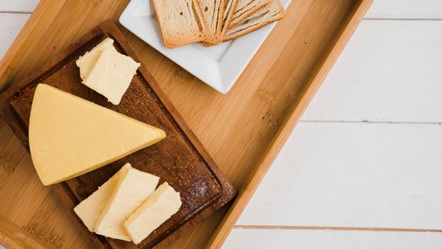 triangular cheese wedges wooden tray against white desk