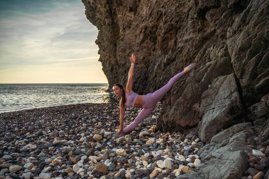 Girl gymnast is training on the beach by the sea. Does twine. Photo series.