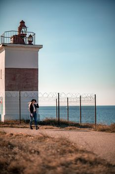 A blonde in a stylish black leather jacket walks along the seashore