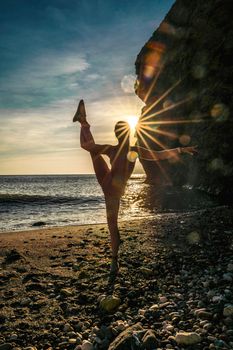 Girl gymnast is training on the beach by the sea sunset. Does twine. Photo series