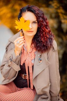 Beautiful girl walking outdoors in autumn. Smiling girl collects yellow leaves in autumn. Young woman enjoying autumn weather