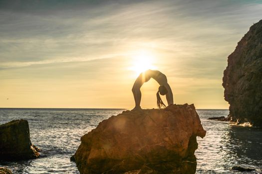 Girl gymnast is training on the beach by the sea sunset. Does twine. Photo series