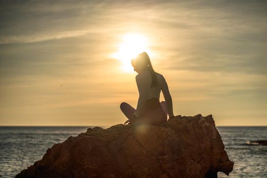 Girl gymnast is training on the beach by the sea sunset. Does twine. Photo series