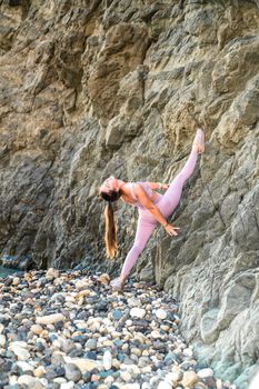 Girl gymnast is training on the beach by the sea. Does twine. Photo series.