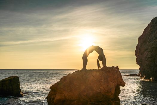 Girl gymnast is training on the beach by the sea sunset. Does twine. Photo series