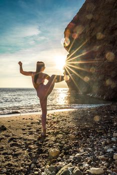 Girl gymnast is training on the beach by the sea sunset. Does twine. Photo series