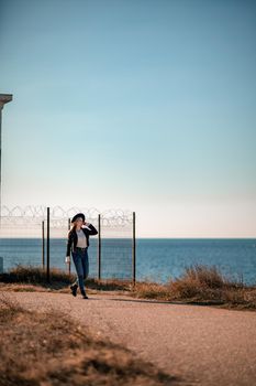 A blonde in a stylish black leather jacket walks along the seashore