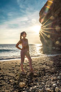 Girl gymnast is training on the beach by the sea sunset. Does twine. Photo series