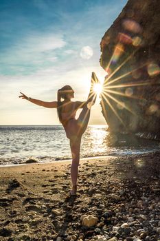 Girl gymnast is training on the beach by the sea sunset. Does twine. Photo series