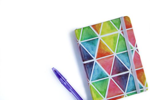 Colorful rainbow notebook with pen on white background. Rainbow colors.