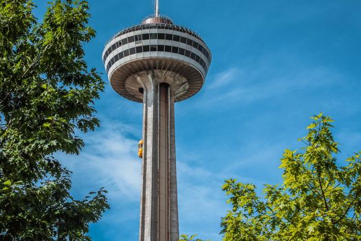 Beautiful view of skylon tower at Niagara falls with blue sky and green trees.