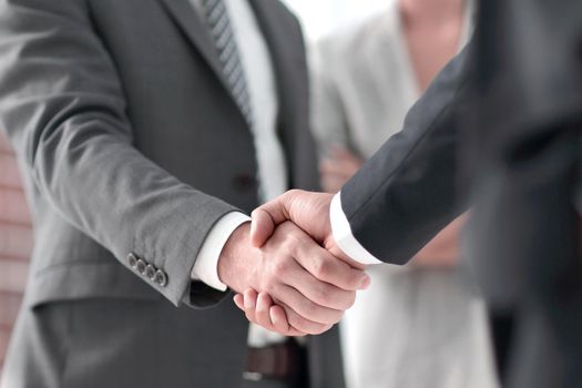 closeup of handshake of business partners on the background of business team