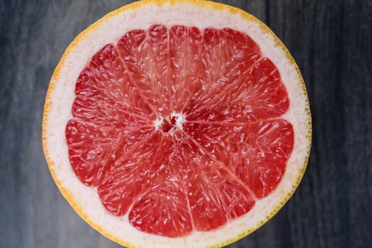 Slices of red grapefruit on the wooden background