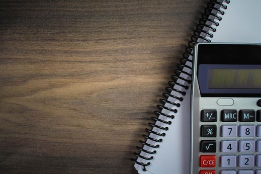 Top view photo of workplace with calculator on notebook on isolated wooden table background with copyspace. Business, coins, bitcoin concept