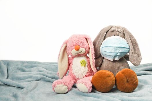 A sick sad plush toy in a mask. Flu colds disease virus bacterium. Plush donkey and pink bunny toy wear protection mask