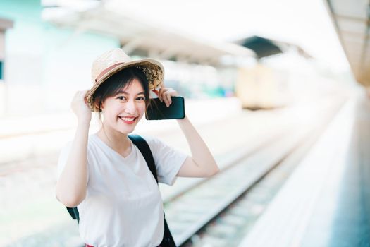 summer, relax, vacation, travel, portrait of cute Asian girl showing smile and showing joy while waiting at the train station for a summer trip