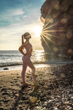 Girl gymnast is training on the beach by the sea sunset. Does twine. Photo series