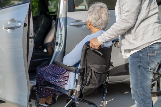 Help and support asian senior or elderly old lady woman patient sitting on wheelchair prepare get to her car, healthy strong medical concept.