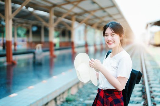 summer, relax, vacation, travel, portrait of cute Asian girl showing smile and showing joy while waiting at the train station for a summer trip