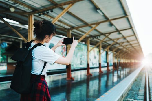 summer, relax, vacation, travel, portrait of beautiful Asian girl using the smartphone mobile take a photo at the train station while waiting for their travel time