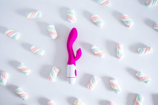 Pink dildo toy with pastel twisted marshmallows isolated on white background.