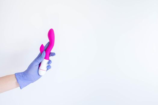 Woman's hand in latex glove holding a pink sex toy - vibrator, isolated on white background
