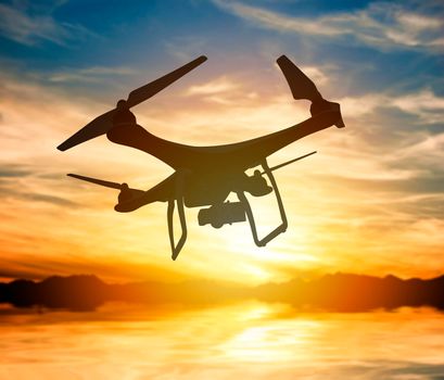 Silhouette of a drone with digital camera flying in a sunset sky: 3D rendering