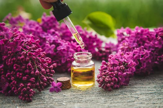 Lilac essential oil in a small bottle. Selective focus. Nature.
