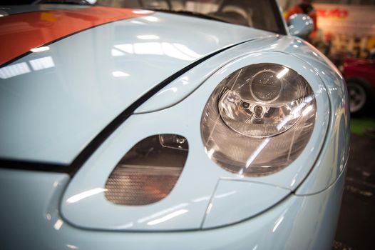 Front of a blue sport car illuminated in a salon