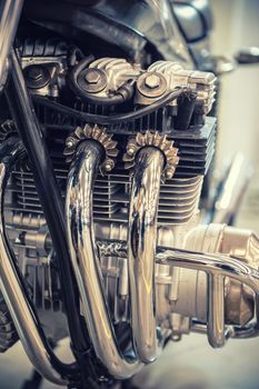 Aged motorcycle engine detail with chrome exhaust pipe