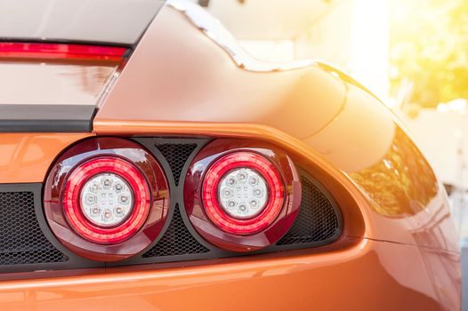 Back of an orange sport luxury car in sunset background