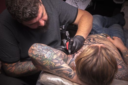 Professional tattoo artist working on professional tattoo machine gun in salon.